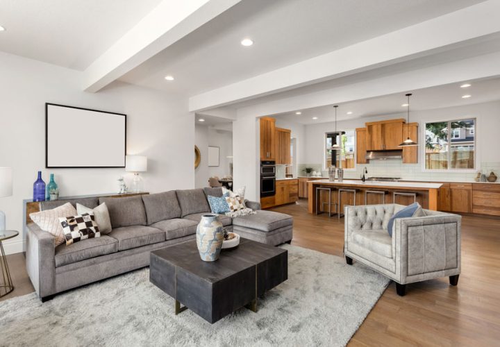 An open plan living space combining a lounge, dining area, and kitchen, with wooden floors, modern furniture, and ample natural light, ideal for family gatherings and entertainment.